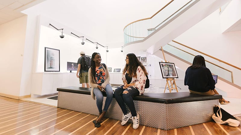Students converse in the lobby of a Full Sail building.