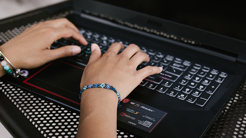 A pair of woman’s hands typing on an MSI GE Raider laptop.