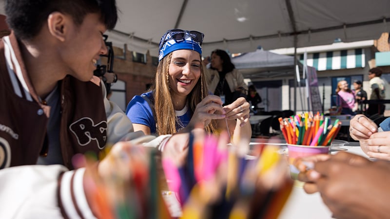 A group of students enjoy crafting together at an outdoor art station filled with colorful pencils.